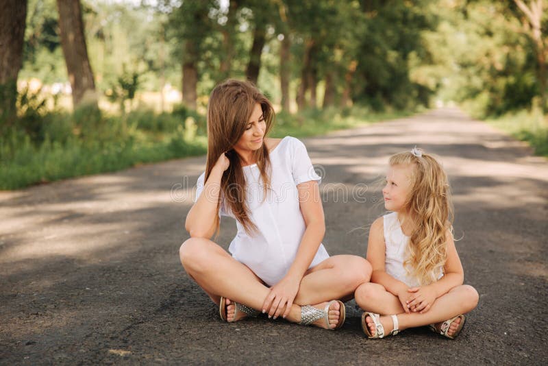 Attractive Mom and Blonde Hair Daughter Sits on Road Near Bi