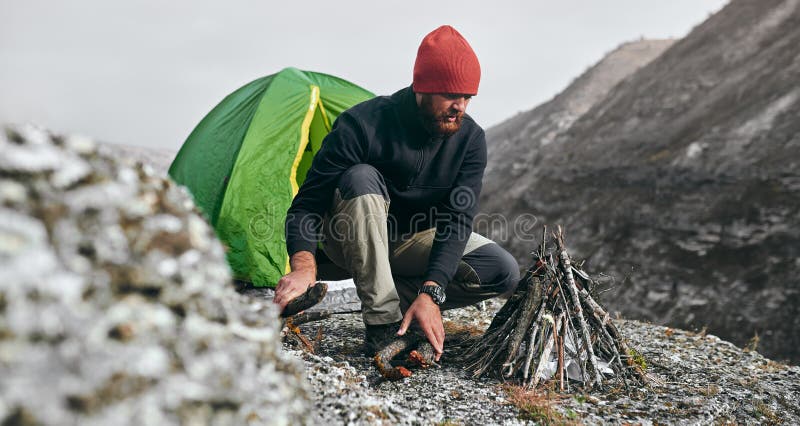La imagen horizontal al aire libre del varón joven del caminante prepara los brunches para la hoguera en montañas Hombre del viaj imagenes de archivo La imagen horizontal al aire libre del varón joven del caminante prepara los brunches para la hoguera en montañas Hombre del viaj imagenes de archivo