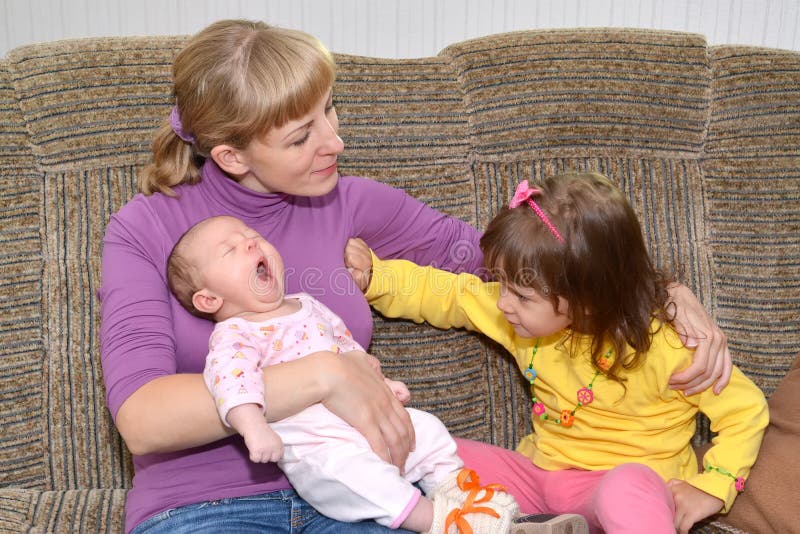 La jalousie des enfants La fille de trois ans éloigne la main de mothera, regardant la petite soeur photographie stock libre de droits La jalousie des enfants La fille de trois ans éloigne la main de mothera, regardant la petite soeur photographie stock libre de droits
