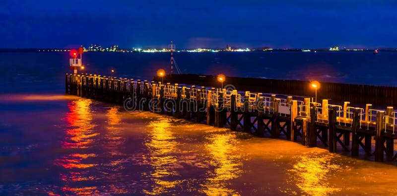 La jetée de pilier du vlissingen illuminée la nuit, lumières se reflétant dans l'océan, Zélande, Hollandes image stock La jetée de pilier du vlissingen illuminée la nuit, lumières se reflétant dans l'océan, Zélande, Hollandes image stock