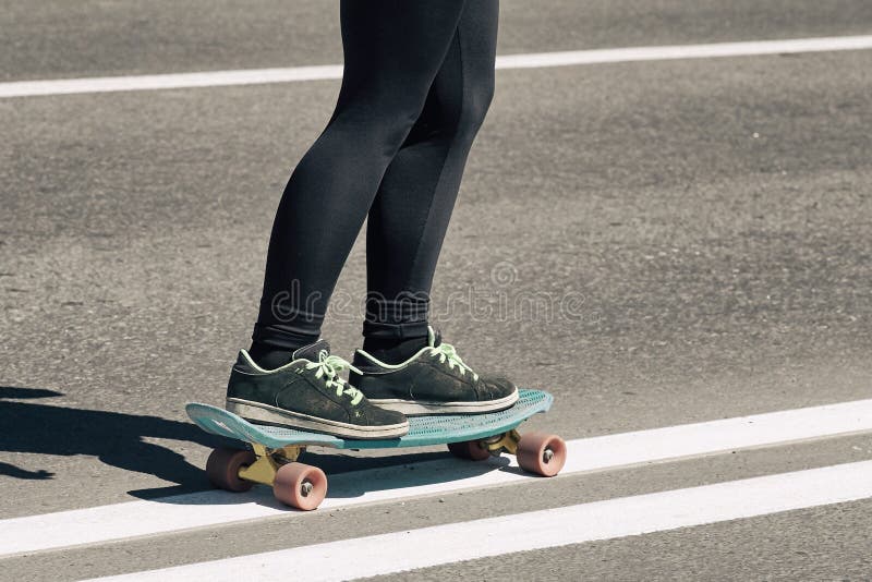 La jeune adolescente de fille de planchiste, patine dangereusement sur la route image stock La jeune adolescente de fille de planchiste, patine dangereusement sur la route image stock
