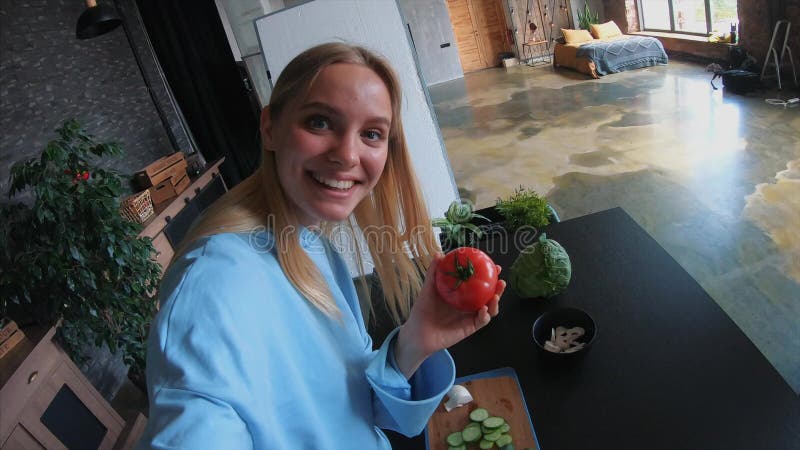 La jeune belle blonde prend des vidéos pendant qu'elle est en train de cuisiner dans la cuisine