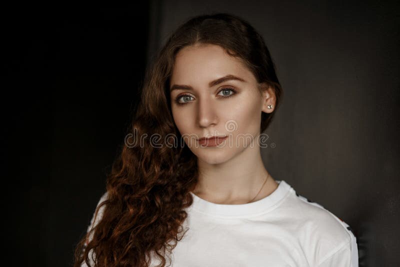 La jeune belle femme attirante dans un T-shirt blanc regarde photographie stock La jeune belle femme attirante dans un T-shirt blanc regarde photographie stock