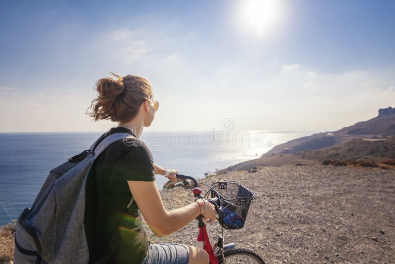 La jeune belle femme de fille voyage en bicyclette sur une terre de montagne image stock La jeune belle femme de fille voyage en bicyclette sur une terre de montagne image stock