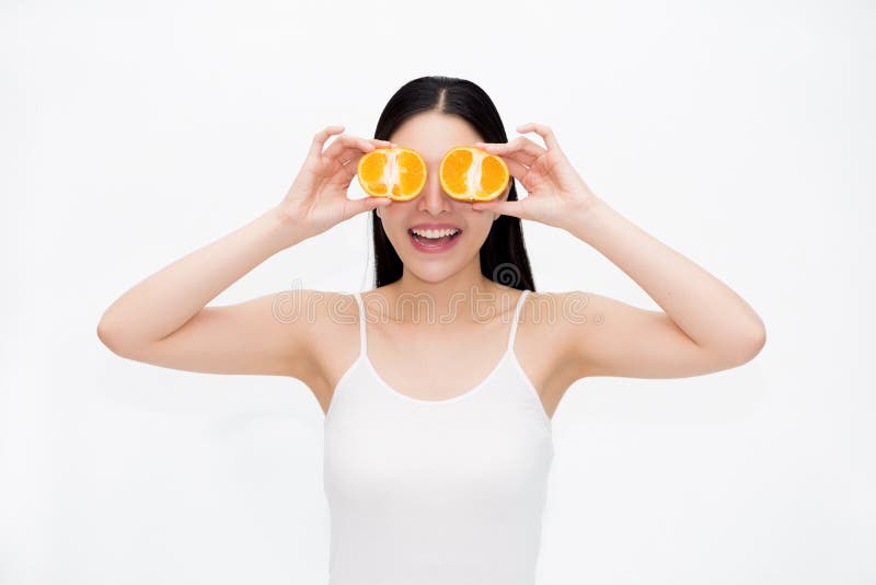 La jeune belle femme de sourire asiatique dans les cheveux noirs et le blanc investissent tenir des morceaux d'oranges d'agrume d photographie stock libre de droits La jeune belle femme de sourire asiatique dans les cheveux noirs et le blanc investissent tenir des morceaux d'oranges d'agrume d photographie stock libre de droits