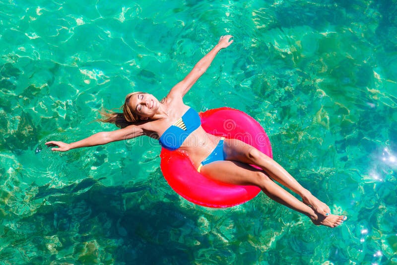 La jeune belle fille dans le bikini nage en mer tropicale sur un rubb photographie stock La jeune belle fille dans le bikini nage en mer tropicale sur un rubb photographie stock
