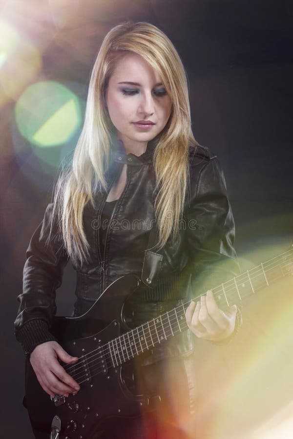 La jeune blonde sexy s'est habillée en cuir noir jouant le GUI électrique photos stock La jeune blonde sexy s'est habillée en cuir noir jouant le GUI électrique photos stock