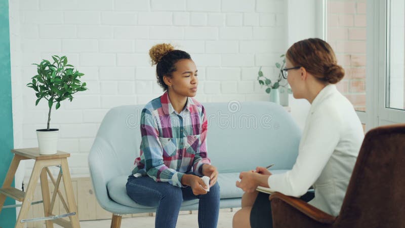 La jeune dame bouleversée dans les vêtements décontractés a la session de thérapie avec le psychologue dans le studio léger La fi banque de vidéos