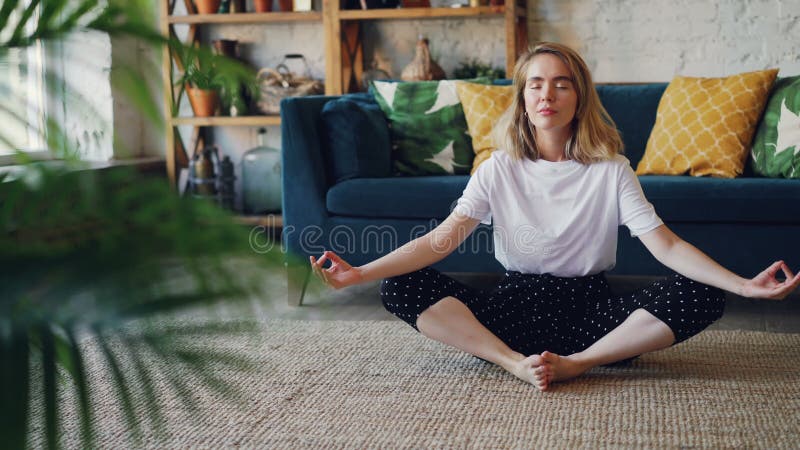 La jeune dame flexible détend dans la pose de pratique de yoga de papillon de position de Badha Konasana à la maison appréciant l