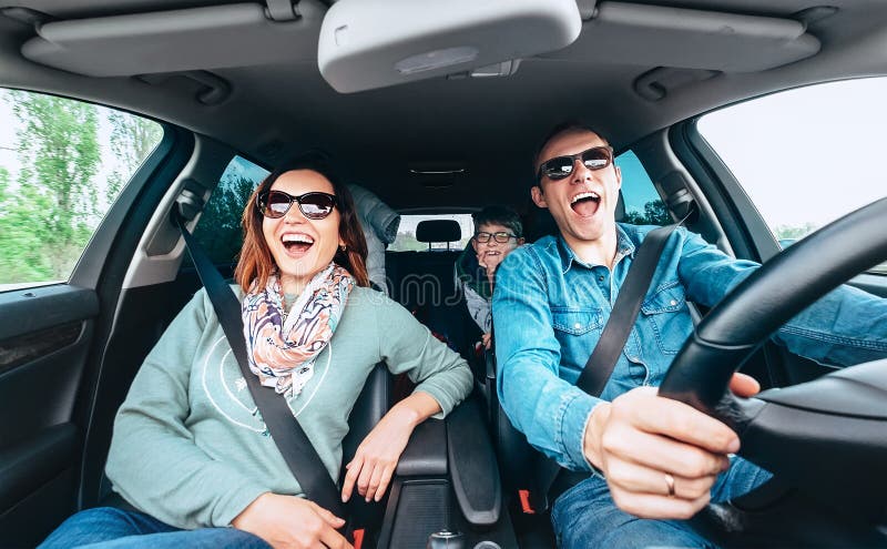 Cheerful young traditional family has a long auto journey and singing aloud the favorite song together. Safety riding car concept wide angle inside car view image. Cheerful young traditional family has a long auto journey and singing aloud the favorite song together. Safety riding car concept wide angle inside car view image