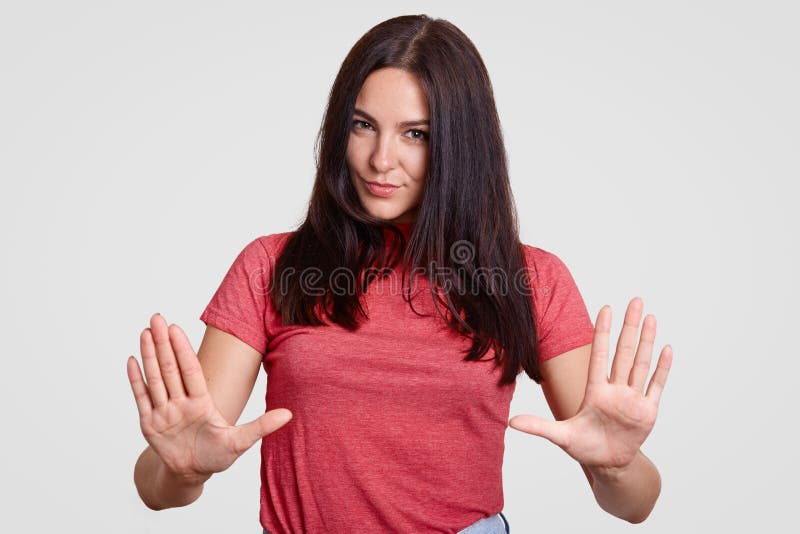 La jeune femelle attirante de brune fait le geste d'arrêt, a l'expression sérieuse, nie faire quelque chose, a longtemps les chev photographie stock La jeune femelle attirante de brune fait le geste d'arrêt, a l'expression sérieuse, nie faire quelque chose, a longtemps les chev photographie stock