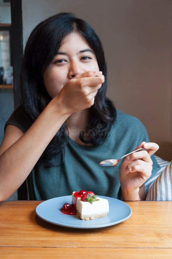 La jeune femme apprécient avec un gâteau en café photographie stock La jeune femme apprécient avec un gâteau en café photographie stock