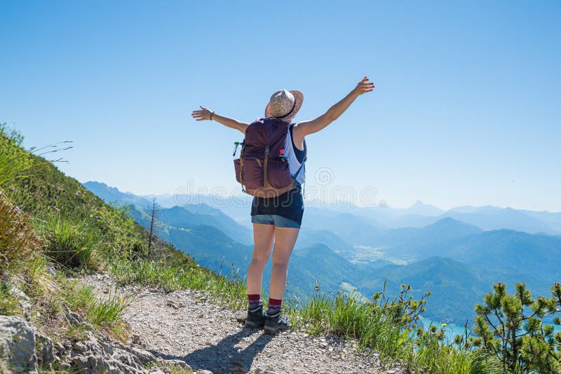 La jeune femme avec les bras tendus apprécient la surveillance à la montagne de herzogstand image stock La jeune femme avec les bras tendus apprécient la surveillance à la montagne de herzogstand image stock