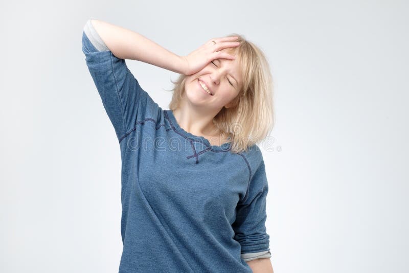 La jeune femme blonde portant le pulover bleu étonné avec la main sur la tête pour l'erreur, se rappellent l'erreur photo libre de droits La jeune femme blonde portant le pulover bleu étonné avec la main sur la tête pour l'erreur, se rappellent l'erreur photo libre de droits