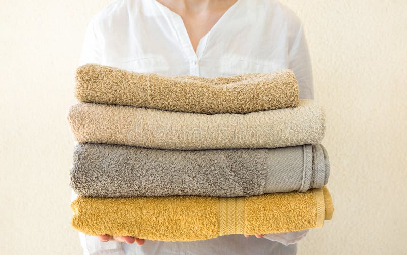 La jeune femme caucasienne se tient dans la pile de mains de serviettes éponge pliées propres Fond blanc de mur Propreté de bien- photo libre de droits La jeune femme caucasienne se tient dans la pile de mains de serviettes éponge pliées propres Fond blanc de mur Propreté de bien- photo libre de droits