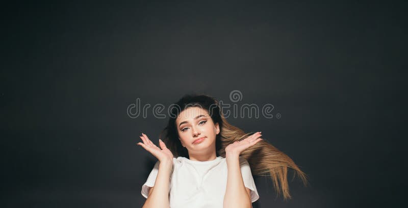 La jeune femme confondue avec de longs cheveux couché sur la fille noire de fond de studio a écarté des armes au choix de vue de d photo stock