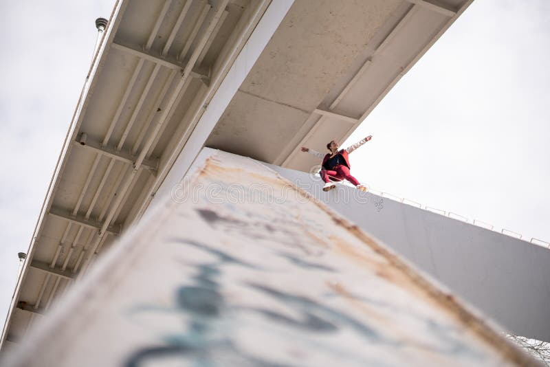 La jeune femme courageuse extrémale s'élèvent sous le pont et l'amusement de avoir Tours dangereux et risque sans assurance photographie stock libre de droits La jeune femme courageuse extrémale s'élèvent sous le pont et l'amusement de avoir Tours dangereux et risque sans assurance photographie stock libre de droits