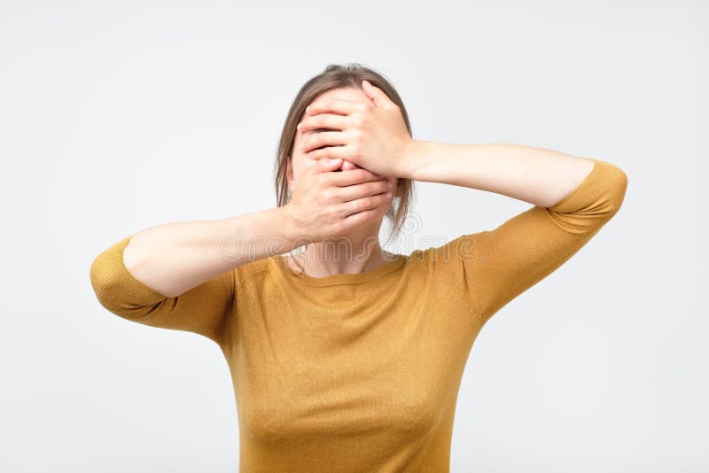 La jeune femme d'affaires cache son visage, photo de studio sur un fond gris image libre de droits La jeune femme d'affaires cache son visage, photo de studio sur un fond gris image libre de droits