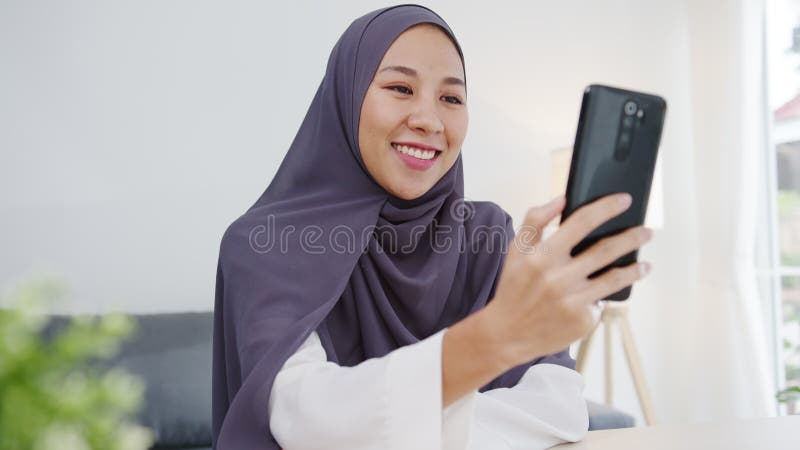 La jeune femme d'affaires musulmane de l'Asie à l'aide de l'entretien de téléphone intelligent à l'ami du brainstorming videochat