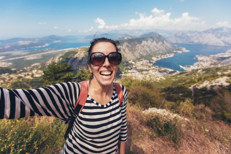 La jeune femme de sourire prend un selfie sur la montagne et la mer de fond photo libre de droits La jeune femme de sourire prend un selfie sur la montagne et la mer de fond photo libre de droits