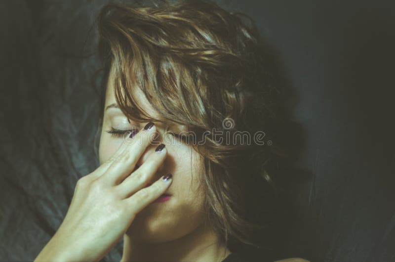 La jeune femme déprimée se sentant malheureuse et seule couvrent son visage de ses mains dans la chambre noire de sa maison image stock La jeune femme déprimée se sentant malheureuse et seule couvrent son visage de ses mains dans la chambre noire de sa maison image stock