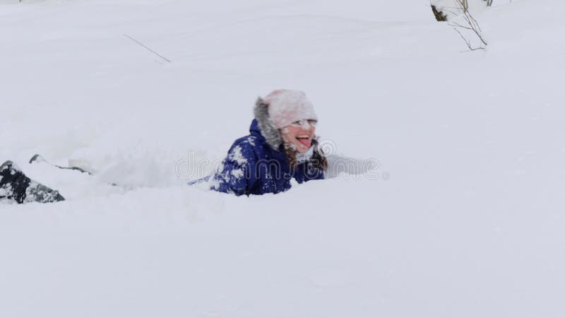 La jeune femme en tenue chaude saute dans la dérive de neige