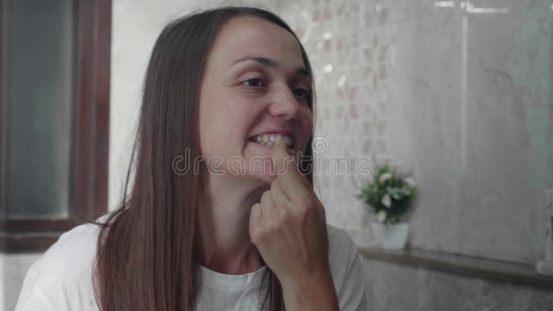 La jeune femme examine ses dents devant le miroir