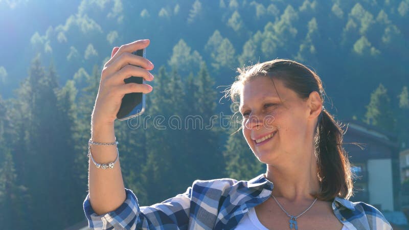 La jeune femme fait un appel vidéo avec son téléphone portable et le salue banque de vidéos