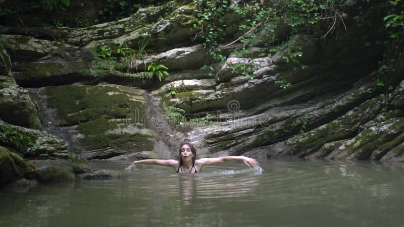 La jeune femme heureuse de mouvement lent éclabousse sur l'eau à la main