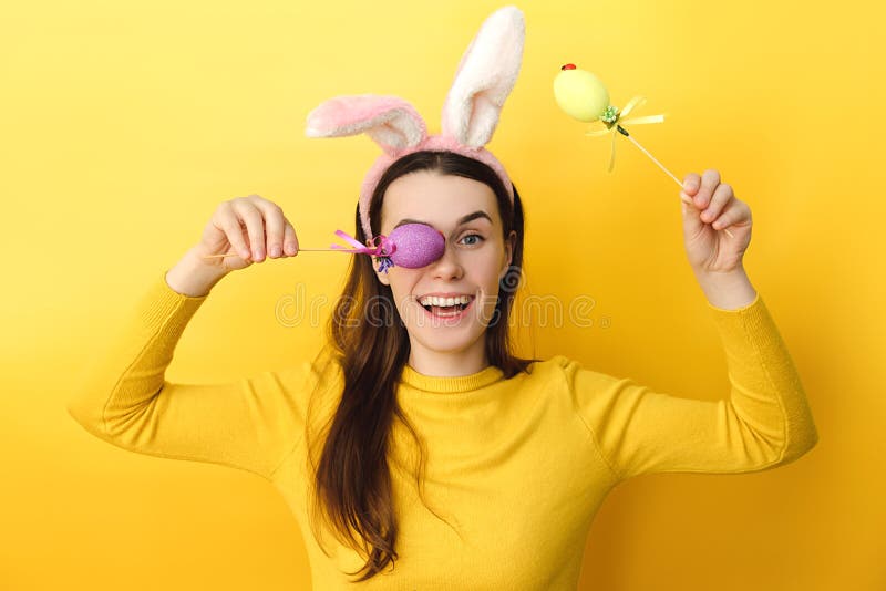 La jeune femme heureuse surprise semble franchement des prises de caméra a peint des oeufs sur les bâtonnets utilise le pull étant images libres de droits