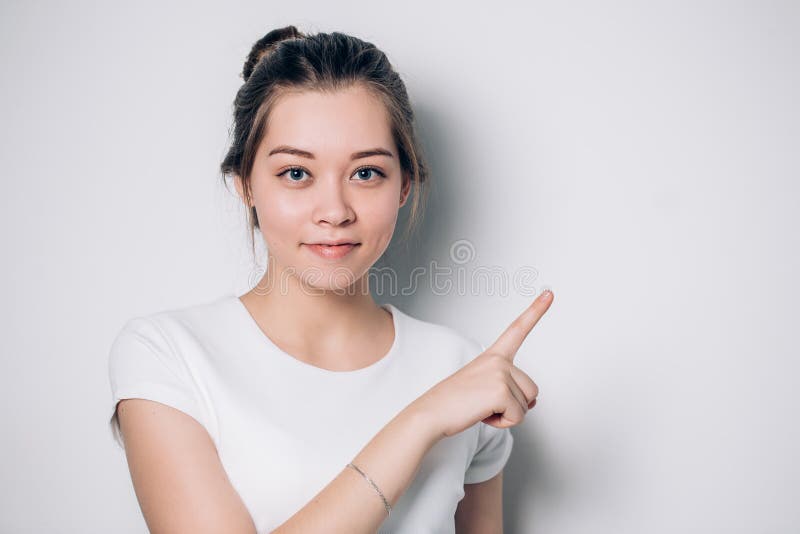 La jeune femme mignonne dirige un doigt loin Présentation de votre produit images stock La jeune femme mignonne dirige un doigt loin Présentation de votre produit images stock