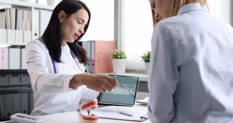 La jeune femme médecin explique les soins dentaires à la patiente banque de vidéos