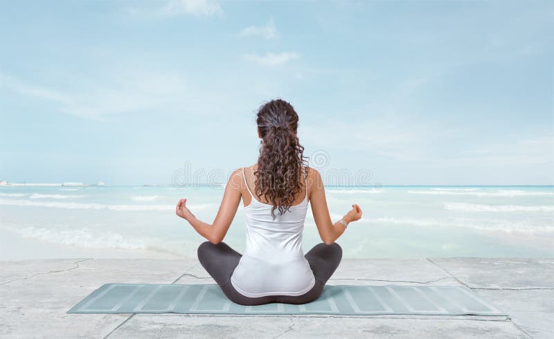 La jeune femme médite sur la plage photographie stock libre de droits La jeune femme médite sur la plage photographie stock libre de droits