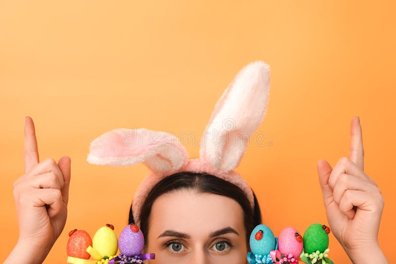 La jeune femme positive utilise les oreilles pelucheuses que les apparences sont confrontés à proximité des oeufs colorés fait le photos stock