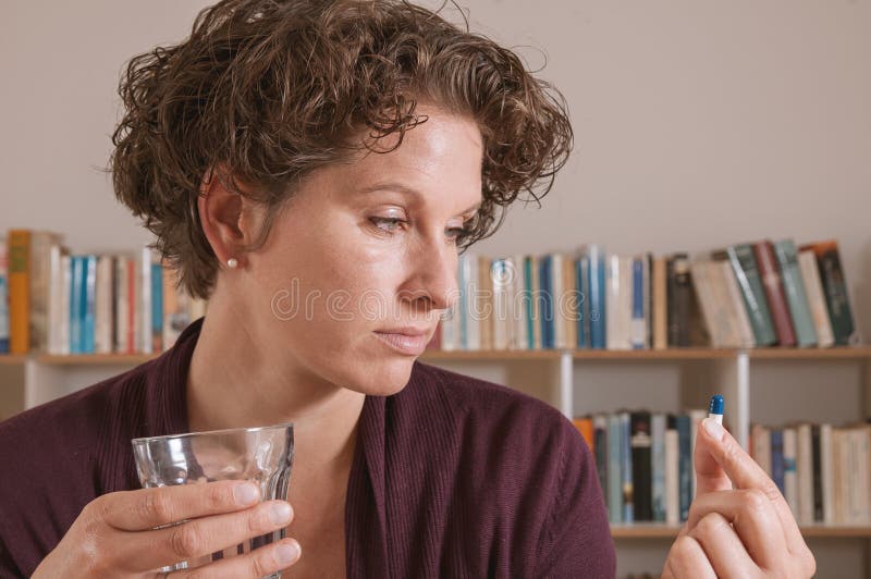 La jeune femme s'est inquiétée de prendre la pilule photo stock La jeune femme s'est inquiétée de prendre la pilule photo stock