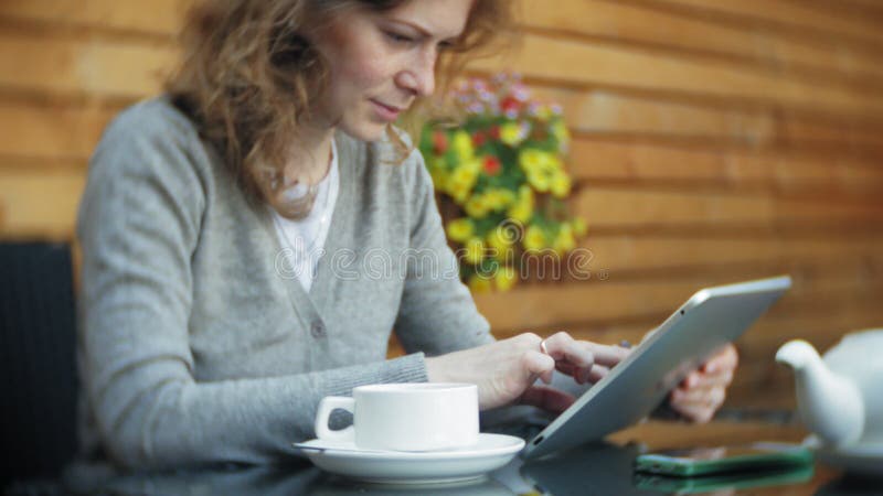 La jeune femme utilise un comprimé et le téléphone, boit du thé dans une barre de café clips vidéos