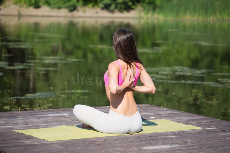 La jeune fille pratique le yoga sur le rivage du lac, le concept d'apprécier l'intimité et la concentration, lumière du soleil photos stock La jeune fille pratique le yoga sur le rivage du lac, le concept d'apprécier l'intimité et la concentration, lumière du soleil photos stock