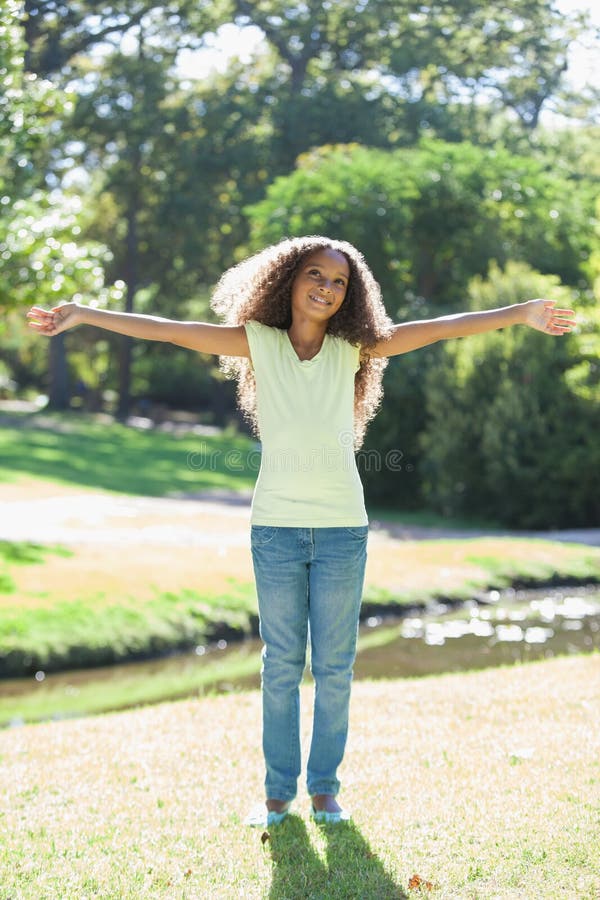 La jeune fille souriant avec des bras a tendu en parc photos stock