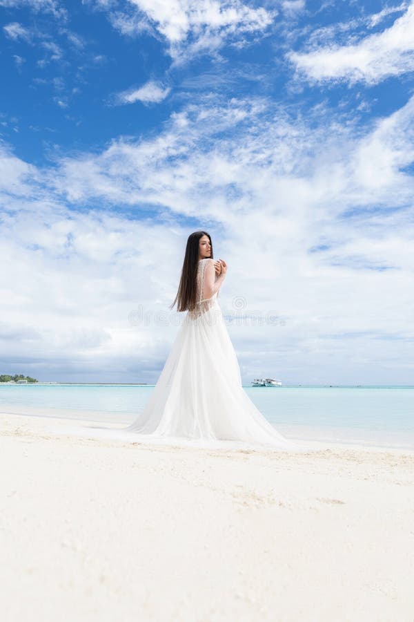 La jeune mariée parfaite Une jeune jeune mariée dans une robe blanche se tient sur une plage blanche comme neige image libre de droits La jeune mariée parfaite Une jeune jeune mariée dans une robe blanche se tient sur une plage blanche comme neige image libre de droits