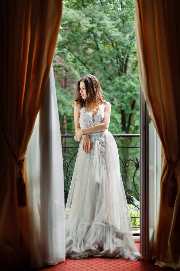 La jeune mariée se tient près de la fenêtre photos libres de droits La jeune mariée se tient près de la fenêtre photos libres de droits