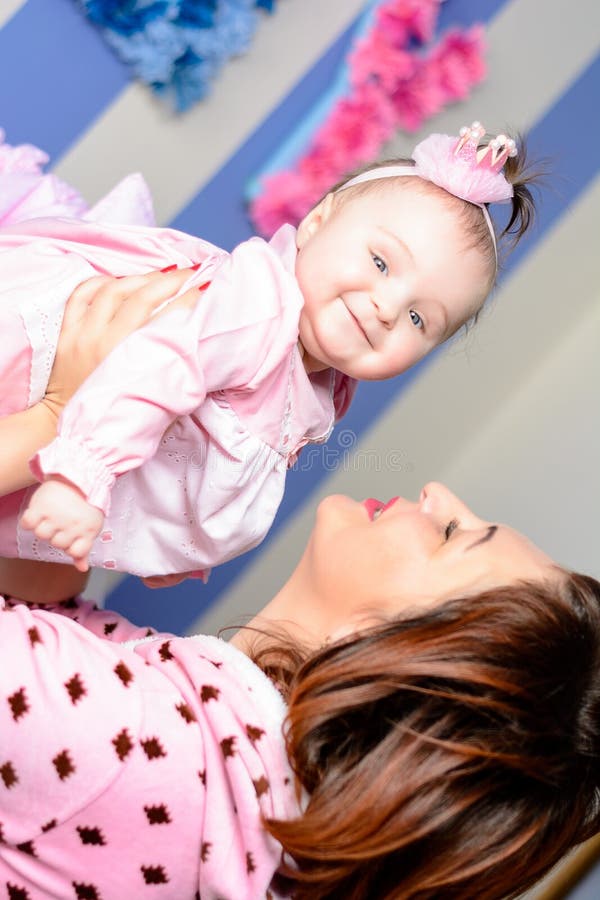 La jeune mère étreint sa petite fille dans la chambre photo stock La jeune mère étreint sa petite fille dans la chambre photo stock