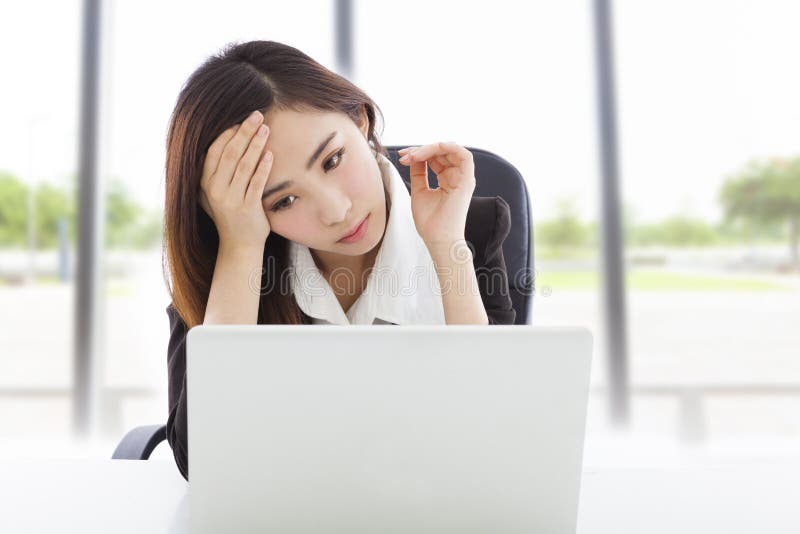 La jeune sensation de femme d'affaires a fatigué et tenant la tête photographie stock libre de droits La jeune sensation de femme d'affaires a fatigué et tenant la tête photographie stock libre de droits