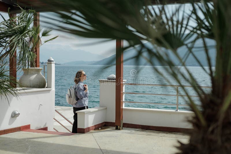 La jolie femme de touristes apprécie la vue de la mer et des montagnes dedans photo libre de droits La jolie femme de touristes apprécie la vue de la mer et des montagnes dedans photo libre de droits