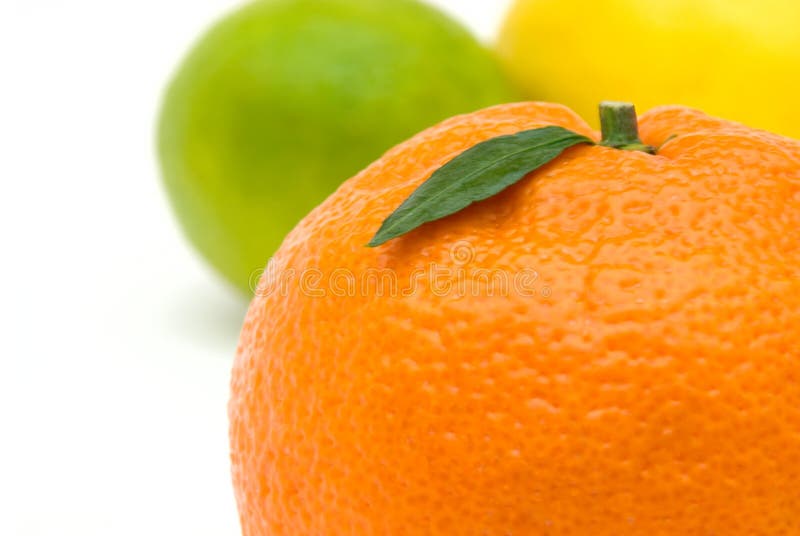 Tangerine with green leaf against vivid background made of lime and lemon. Tangerine with green leaf against vivid background made of lime and lemon