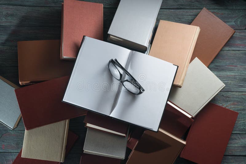 La libro con copertina rigida del libro aperto sulla pila prenota su fondo di legno immagine stock libera da diritti La libro con copertina rigida del libro aperto sulla pila prenota su fondo di legno immagine stock libera da diritti