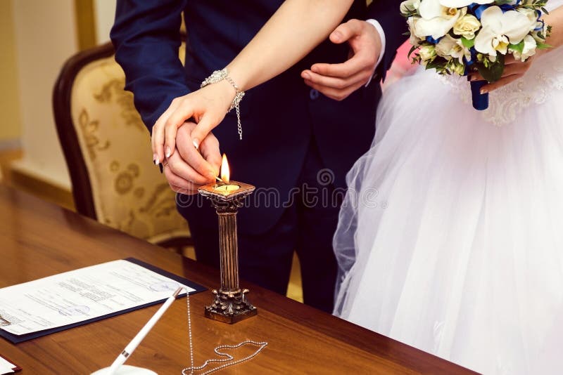 La luce dello sposo e della sposa un la candela fotografia stock La luce dello sposo e della sposa un la candela fotografia stock