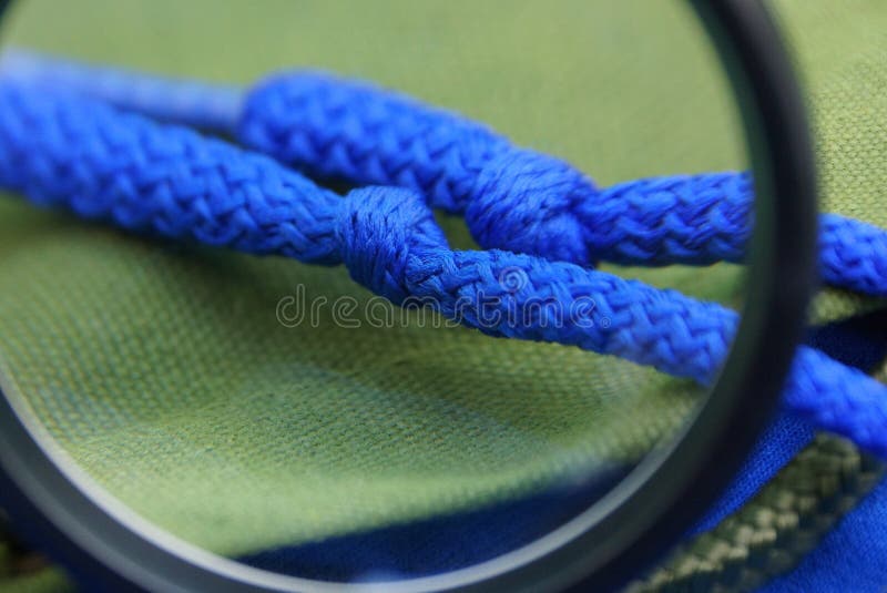 Una lupa negra agranda dos cordones azules con los nudos en materia verde