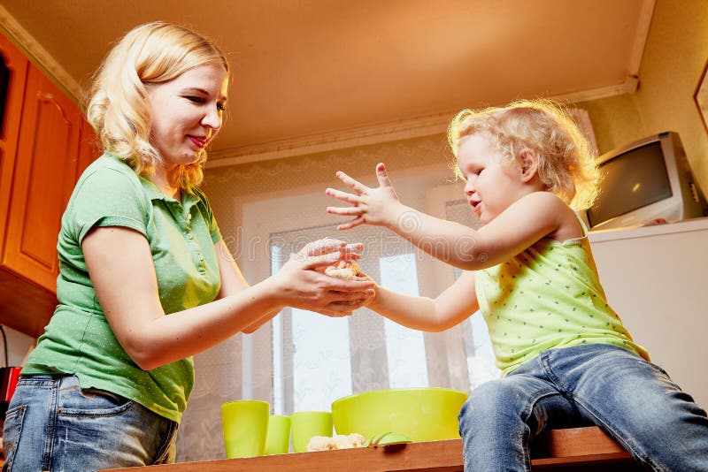 La m?re et ses trois ann?es de fille blonde font cuire dans une cuisine Maman heureuse et petite fille avec la pâte photos libres de droits La m?re et ses trois ann?es de fille blonde font cuire dans une cuisine Maman heureuse et petite fille avec la pâte photos libres de droits