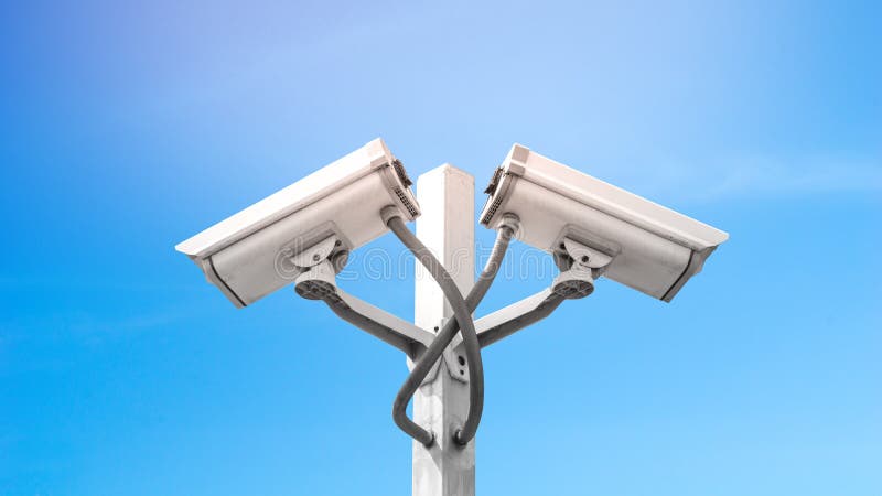 La macchina fotografica doppia del cctv di sorveglianza sul palo con cielo blu e svasarsi effetto della luce, usa per la videosor immagine stock libera da diritti La macchina fotografica doppia del cctv di sorveglianza sul palo con cielo blu e svasarsi effetto della luce, usa per la videosor immagine stock libera da diritti