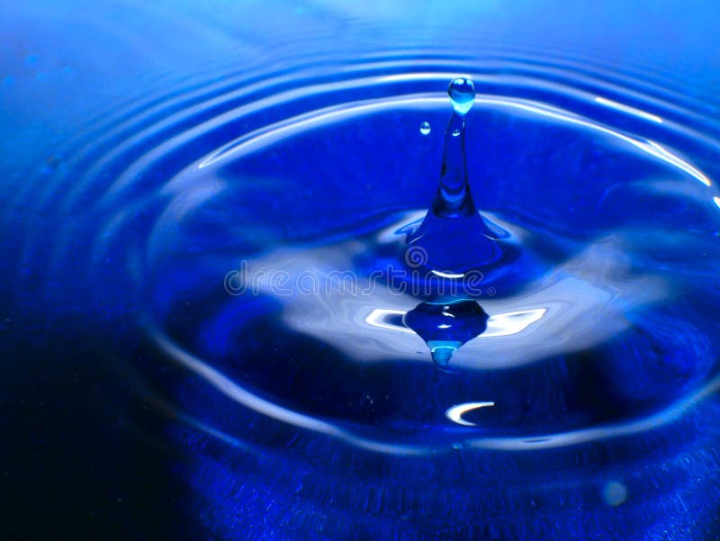 La macrofotografia di una goccia di acqua blu scuro/delle gocce dell'inchiostro spruzza ed ondulazioni, bagnato, concettuali per